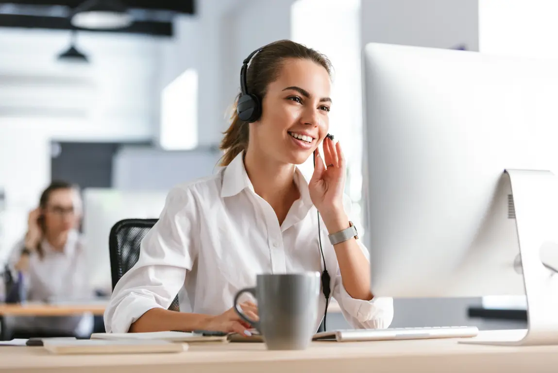 Lächelnde TMA Telesmart Kundenservice-Mitarbeiterin mit Headset am Bildschirm